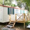 Una casa mobile con terrazza in legno e lettini, circondata da alberi.