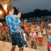 Due animatori in camicia hawaiana intrattengono un gruppo di bambini davanti a un palco.