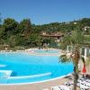 Piscina tonda con una piccola fontana, circondata da lettini e vegetazione lussureggiante.