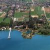 Vista aerea di un'area rurale con campi, edifici e un lago con un pontile bianco.