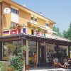 Un edificio giallo con veranda, bandiere appese e persone sedute all'esterno.