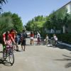 Persone in bici in un cortile alberato.