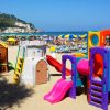 Area giochi per bambini sulla spiaggia, con scivoli colorati.
