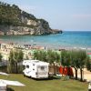 Spiaggia con camper, ombrelloni e mare.