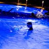 Bambino in una piscina illuminata di notte.